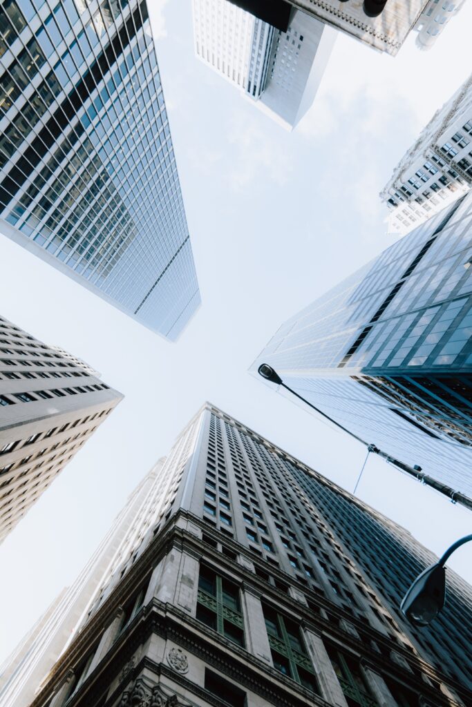 vertical low angle shot of the skyscrapers under the bright sky in new york city, united states